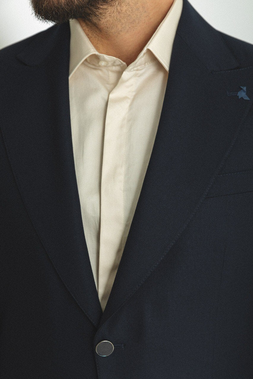 Man wearing a navy blue 2-piece suit with brown shoes.