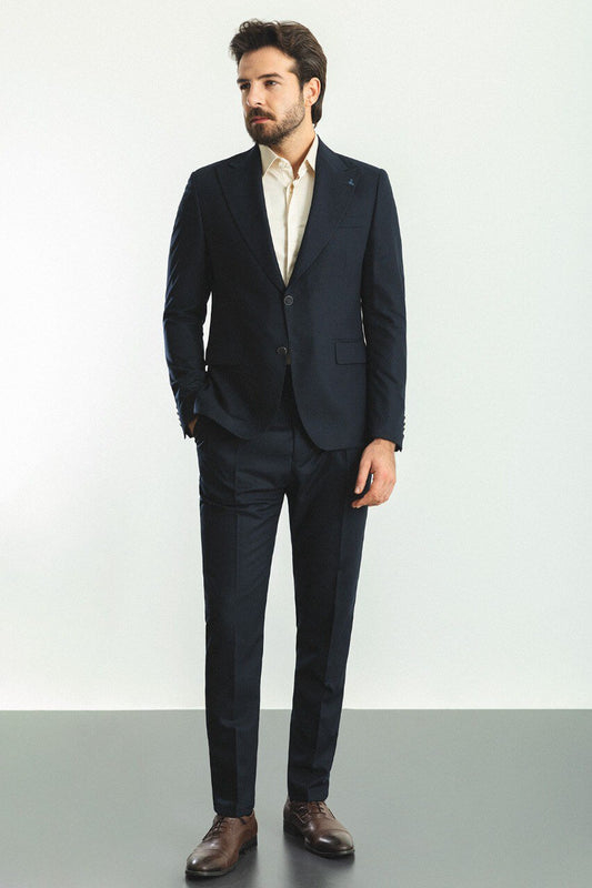 Man wearing a navy blue 2-piece suit with brown shoes.