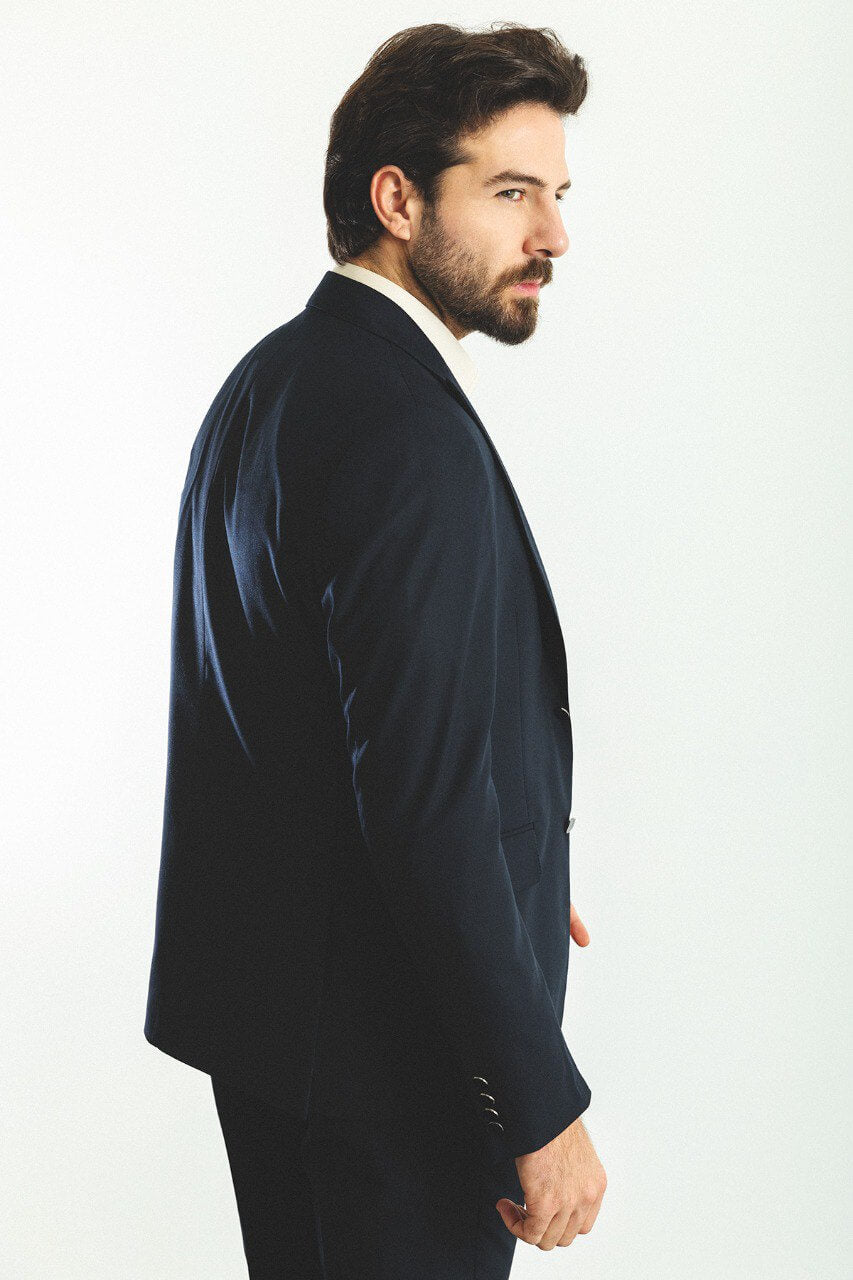 Man wearing a navy blue 2-piece suit with brown shoes.