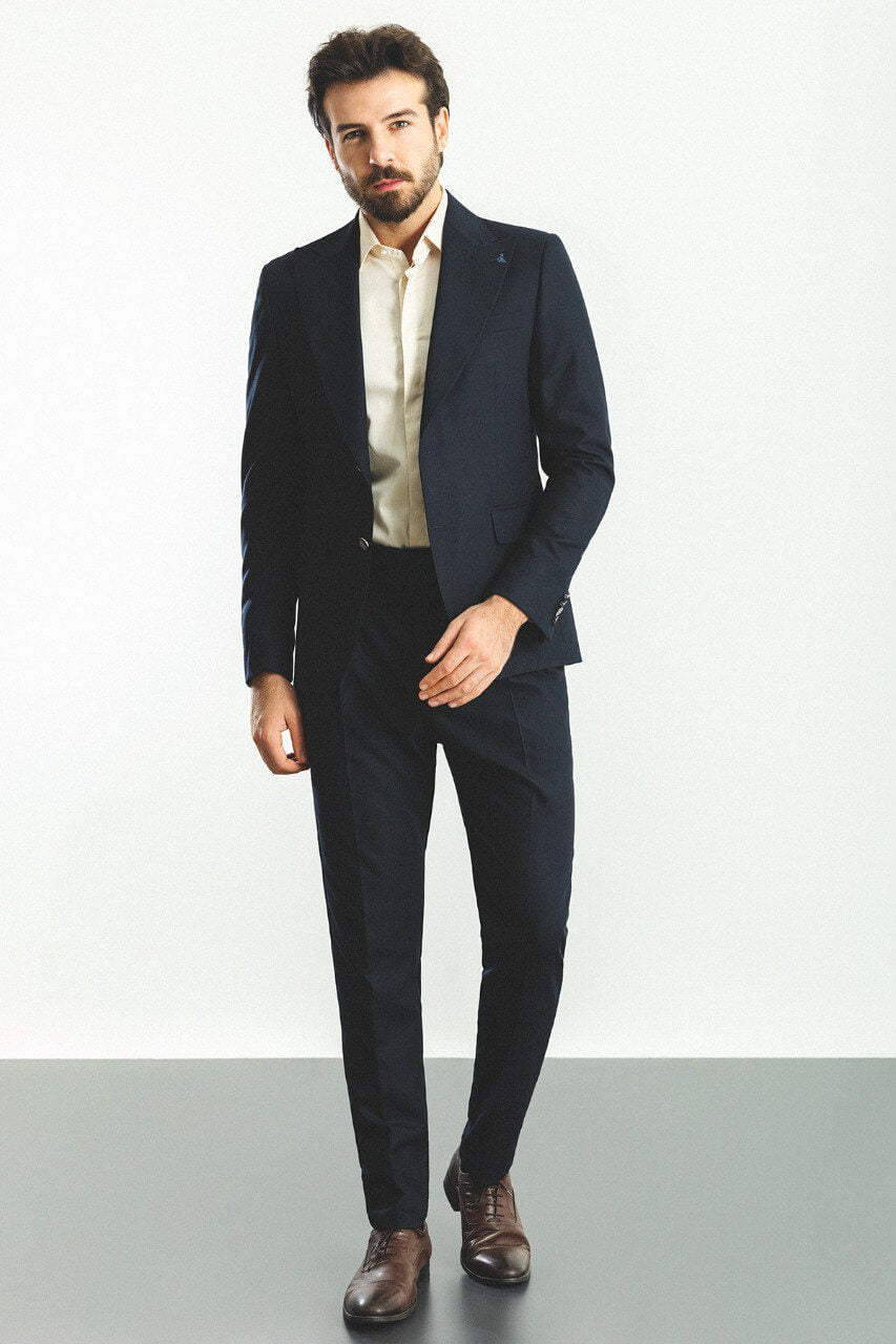 Man wearing a navy blue 2-piece suit with brown shoes.