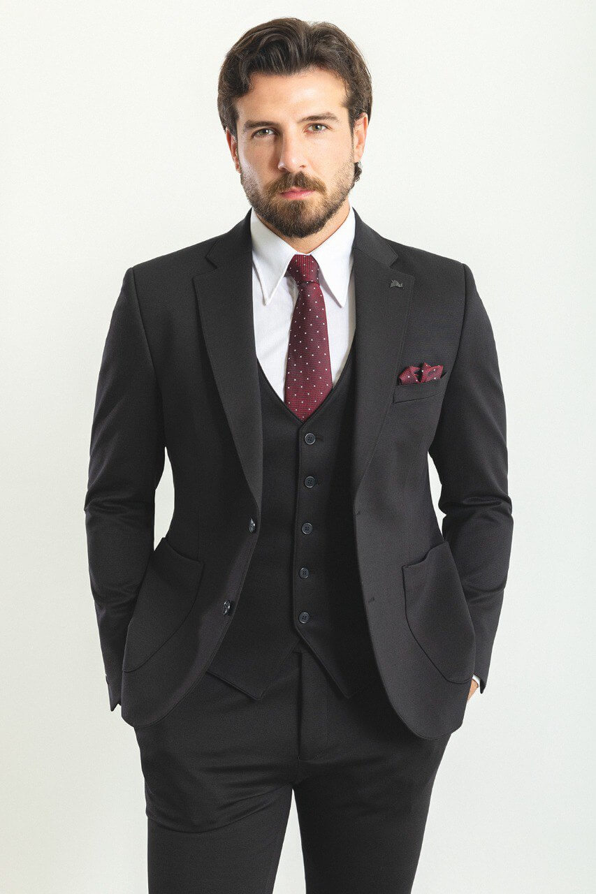 Man in a black 3-piece suit with a burgundy tie and pocket square.