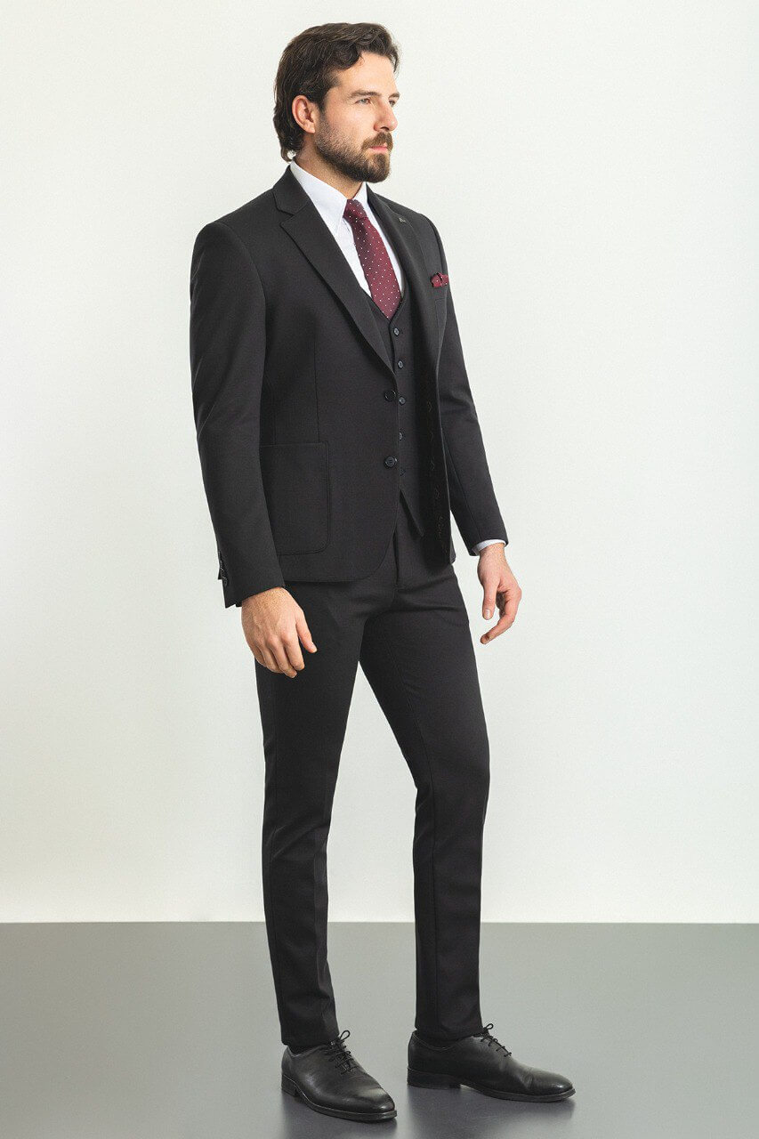 Man in a black 3-piece suit with a burgundy tie and pocket square.