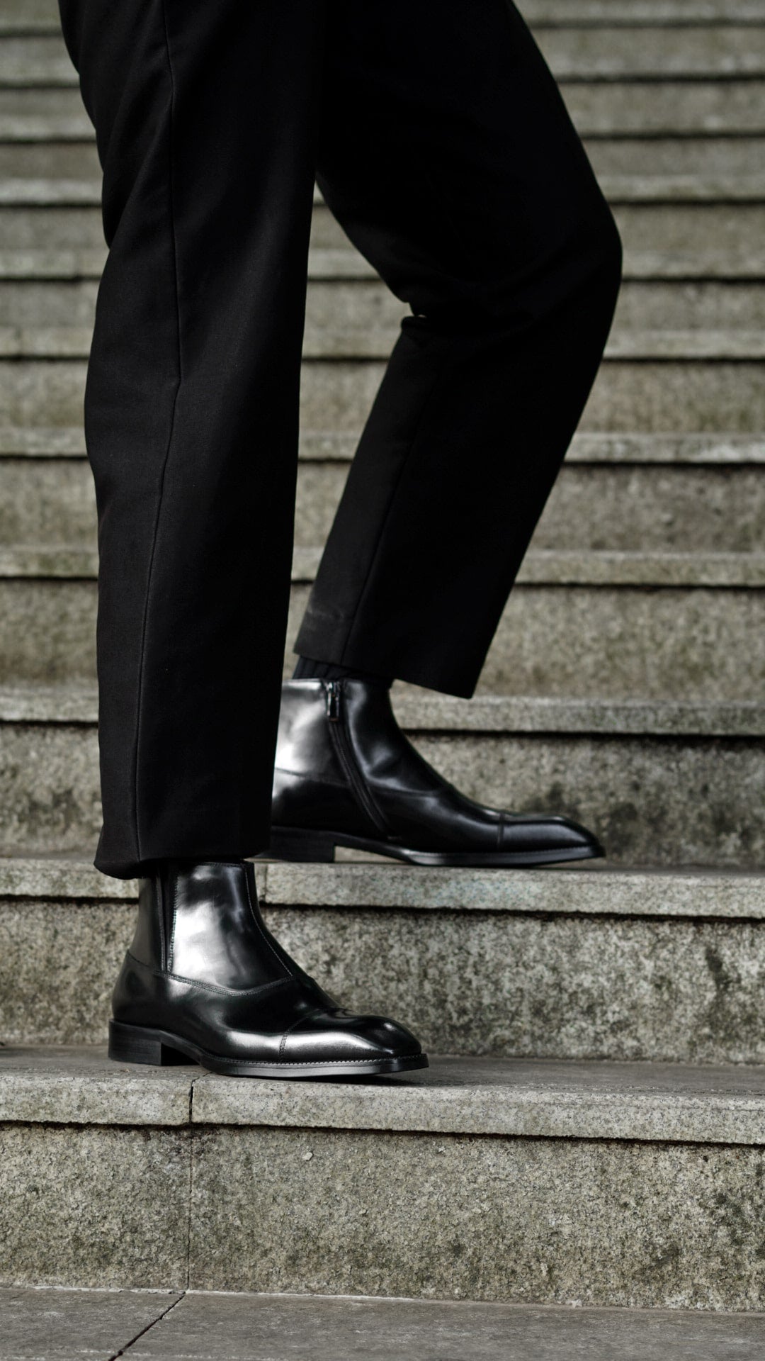 A pair of polished black leather Chelsea boots with a sleek design, ideal for formal wear and business occasions.