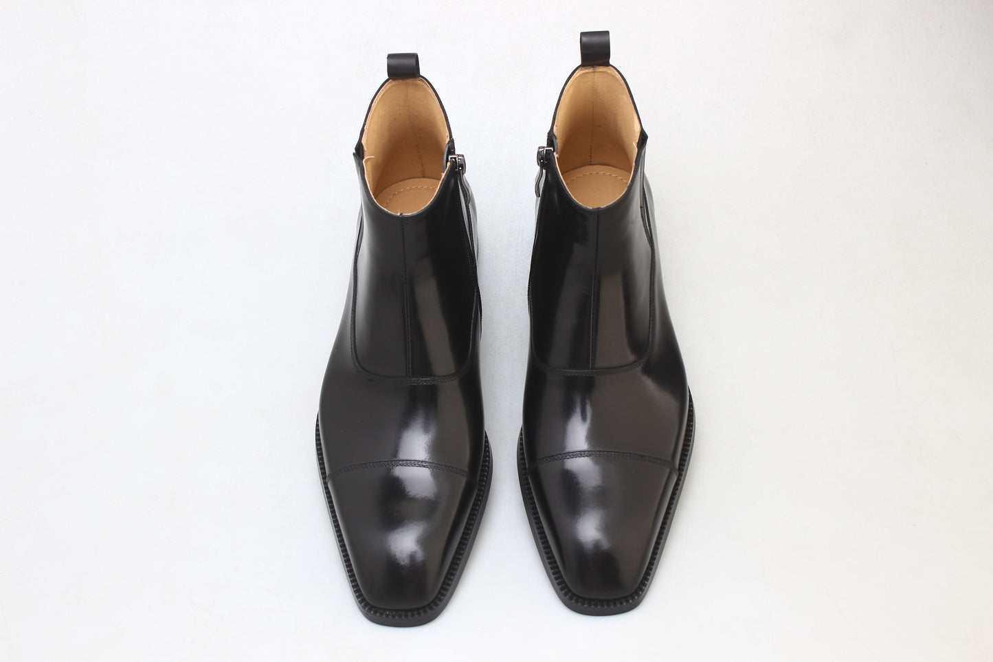 A pair of polished black leather Chelsea boots with a sleek design, ideal for formal wear and business occasions.