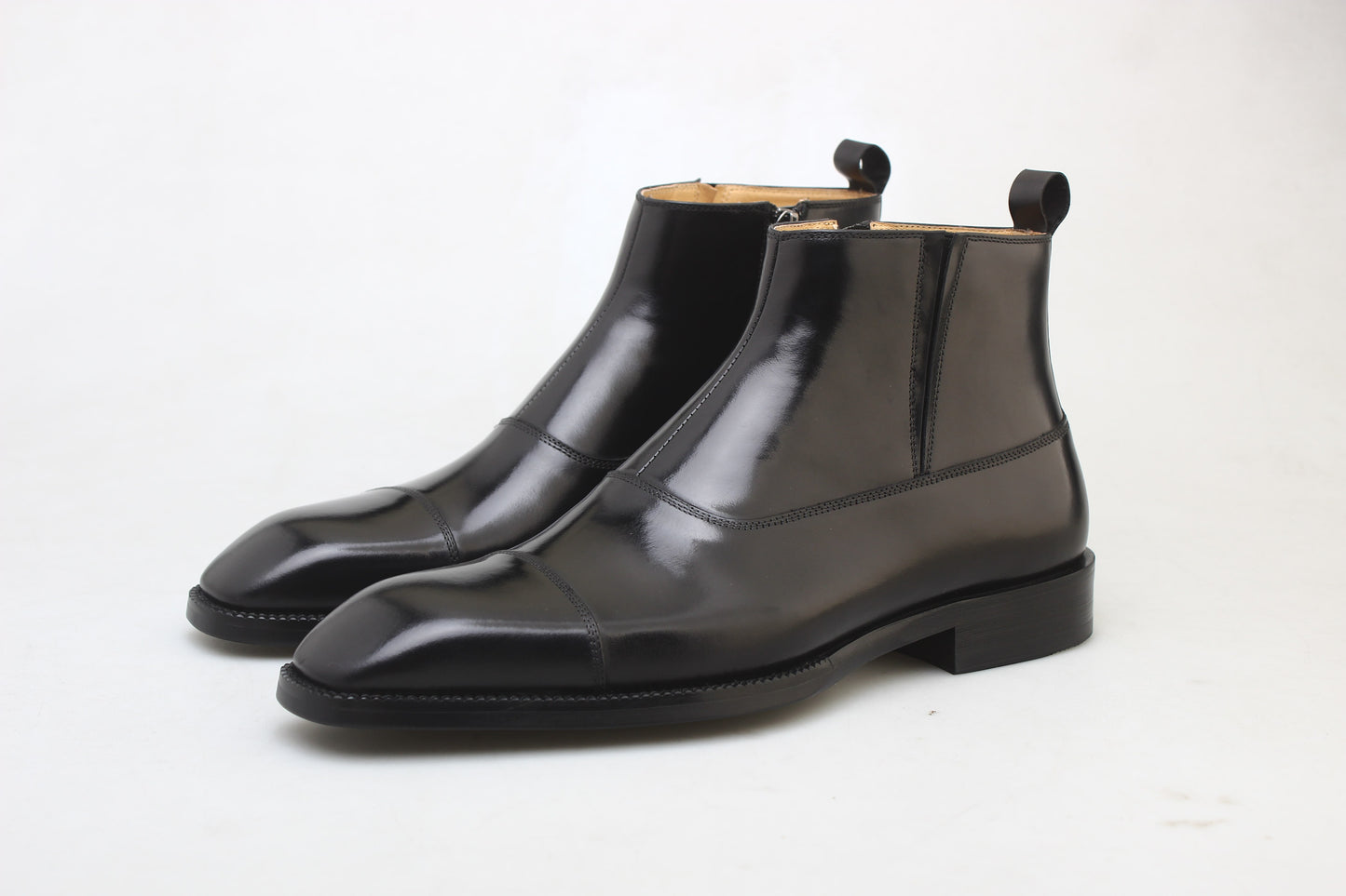 A pair of polished black leather Chelsea boots with a sleek design, ideal for formal wear and business occasions.