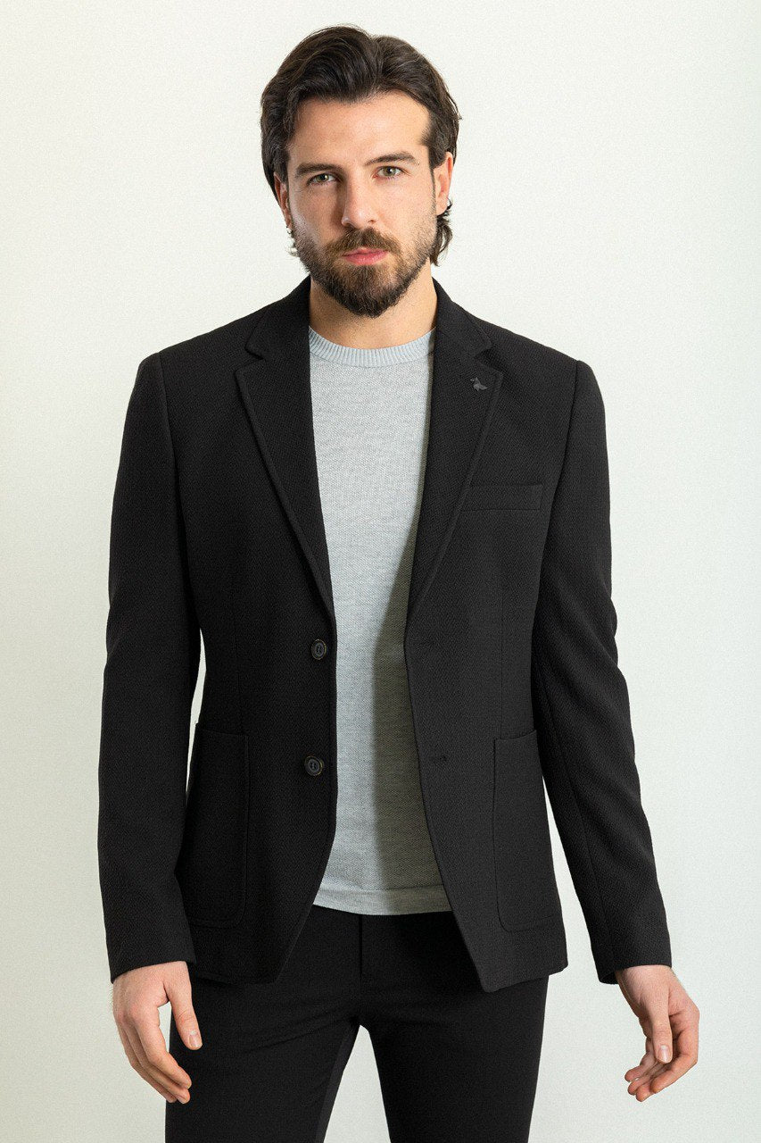 Man wearing a black blazer paired with a light grey sweater.