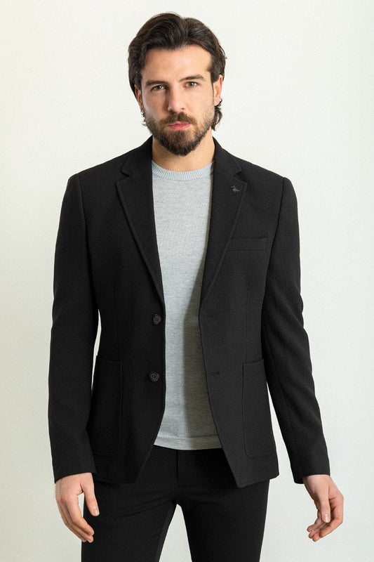 Man wearing a black blazer paired with a light grey sweater.