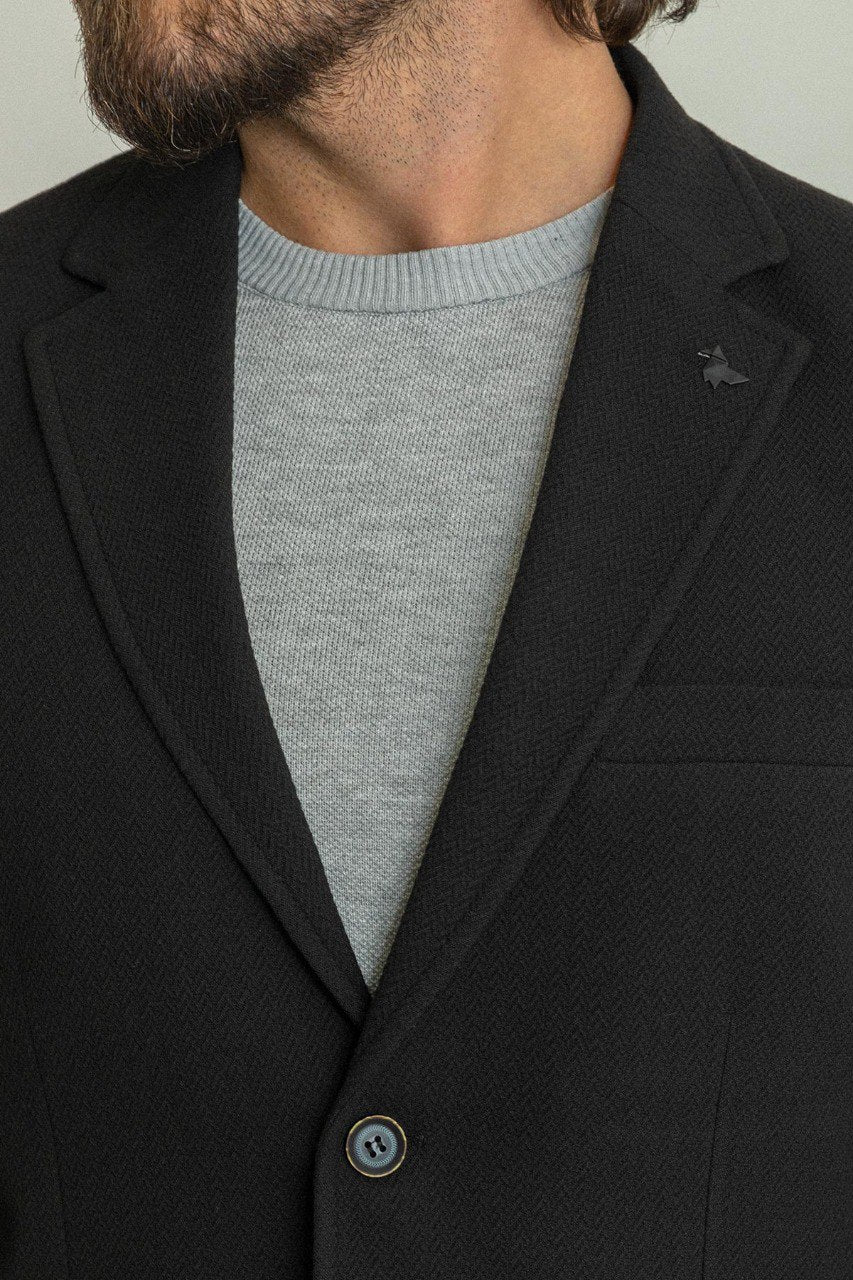 Man wearing a black blazer paired with a light grey sweater.