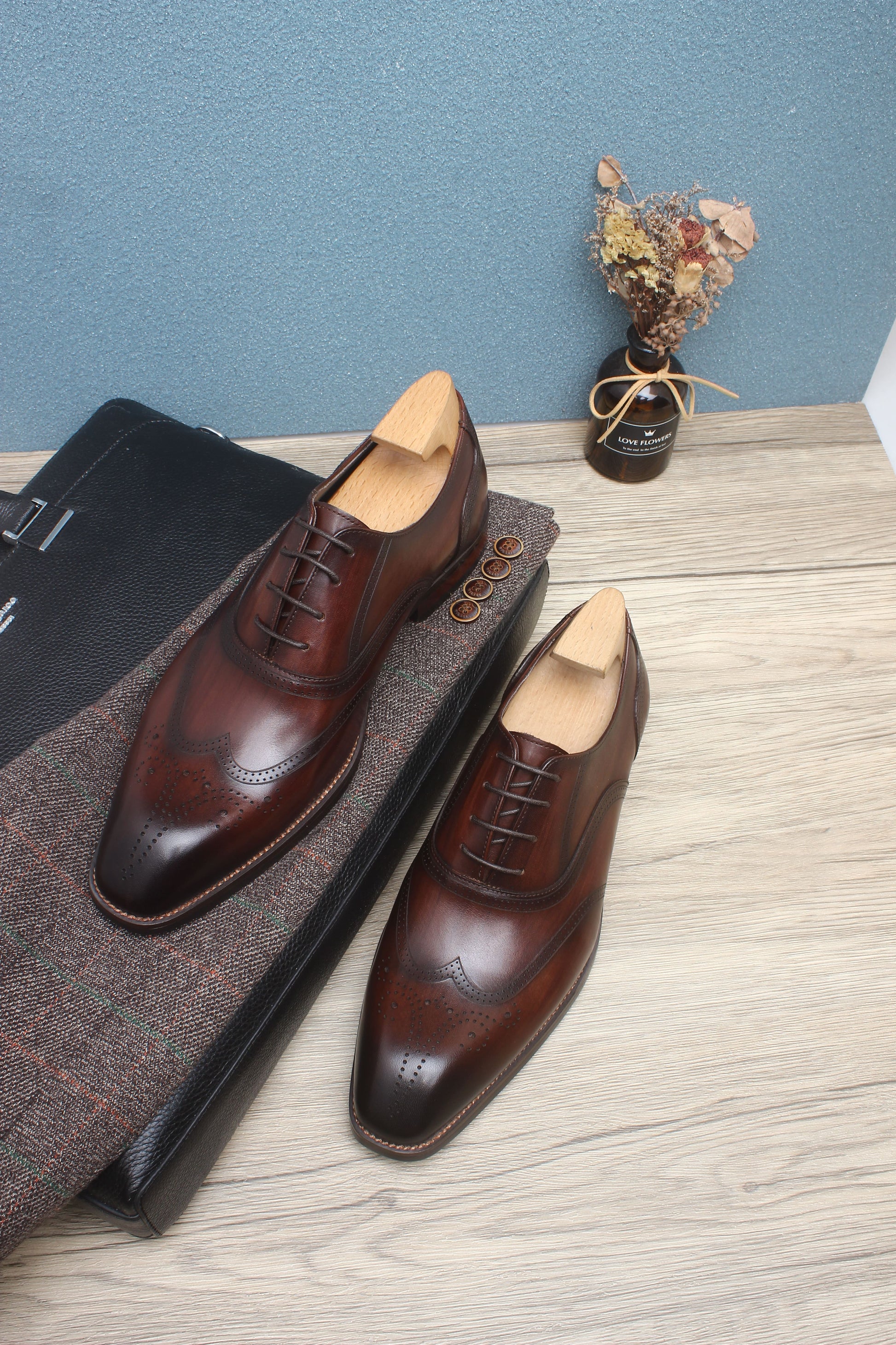 A pair of handcrafted brown leather oxford shoes with wingtip detailing, showcasing elegant design and premium craftsmanship.