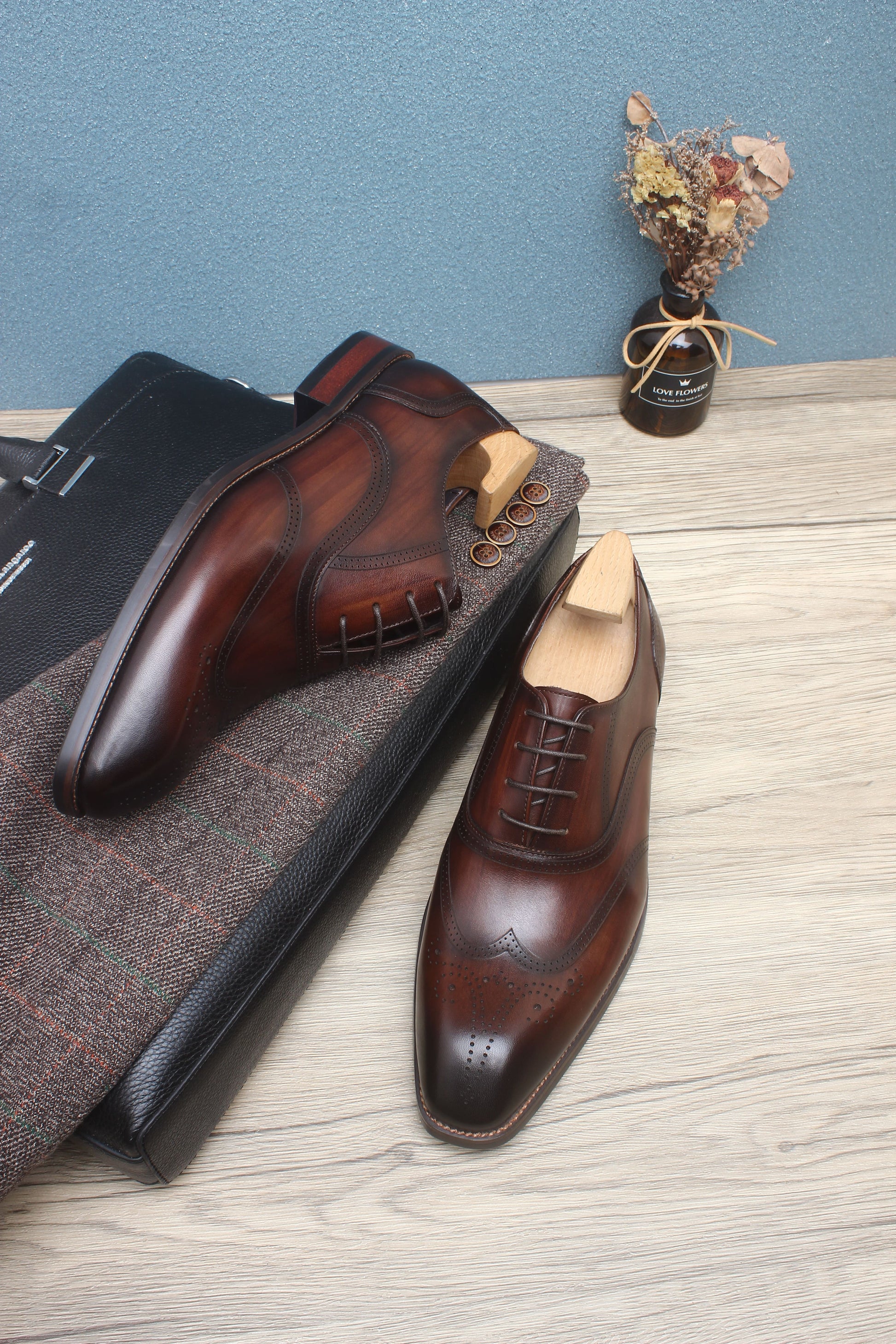 A pair of handcrafted brown leather oxford shoes with wingtip detailing, showcasing elegant design and premium craftsmanship.