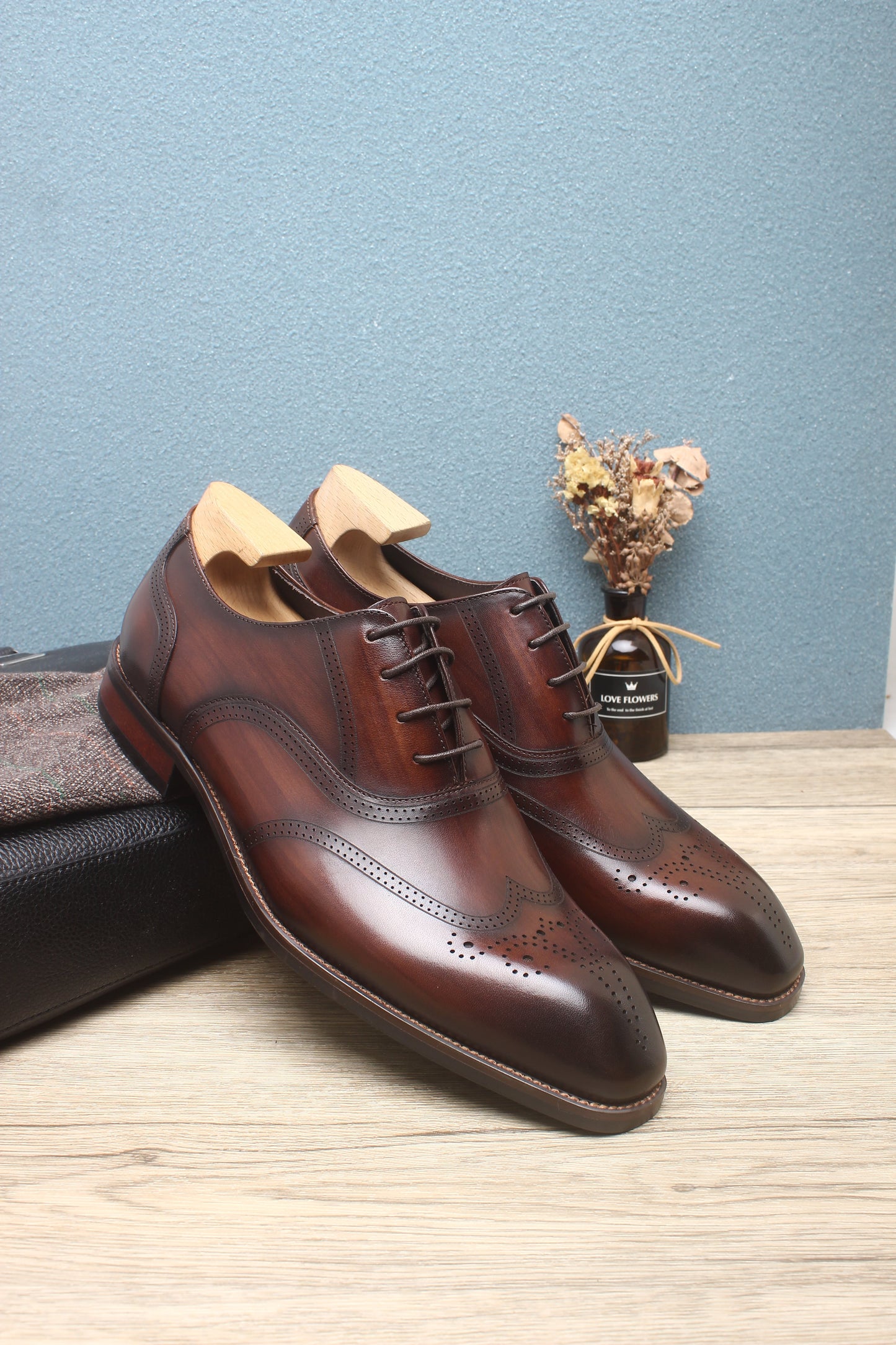 A pair of handcrafted brown leather oxford shoes with wingtip detailing, showcasing elegant design and premium craftsmanship.