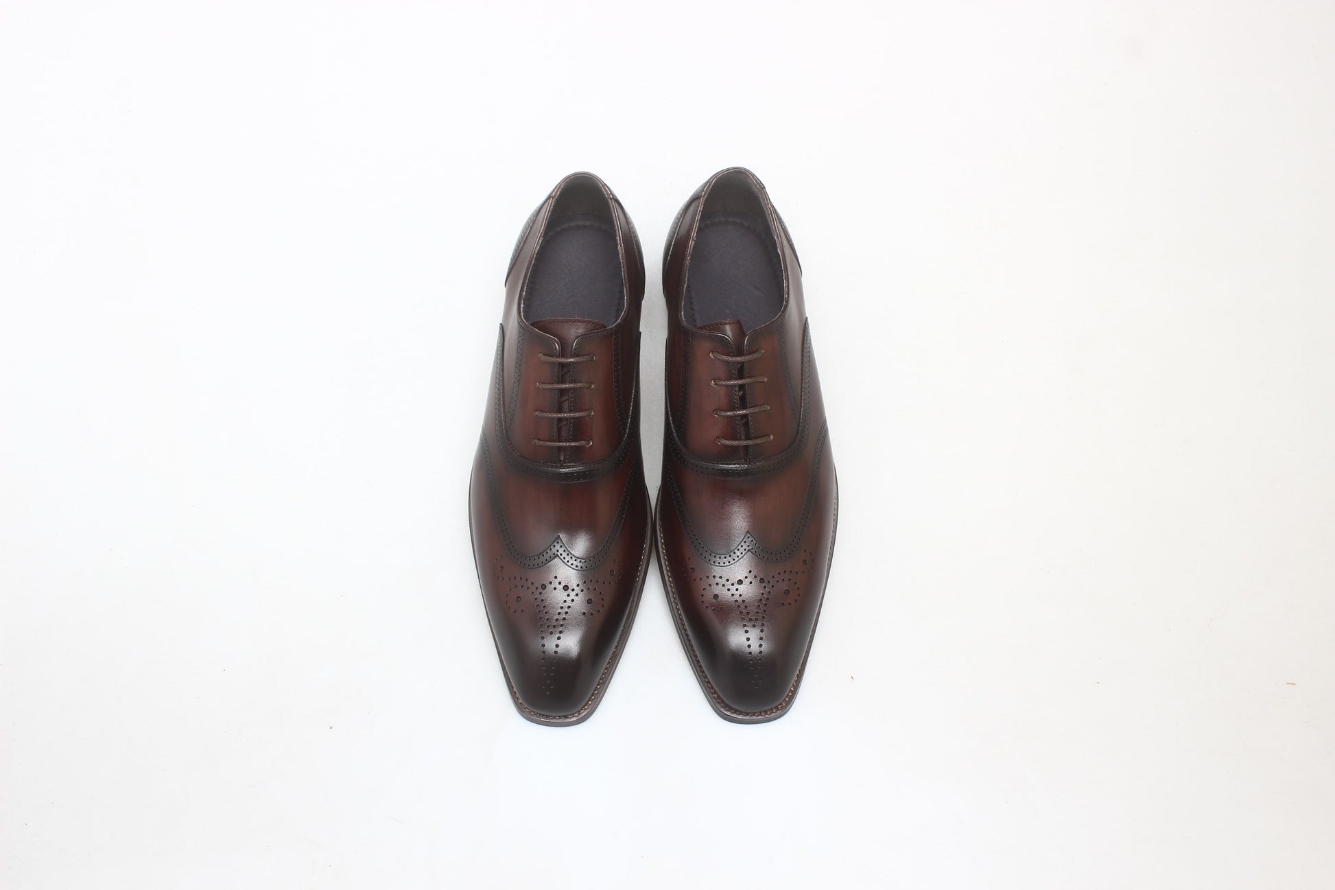 A pair of handcrafted brown leather oxford shoes with wingtip detailing, showcasing elegant design and premium craftsmanship.
