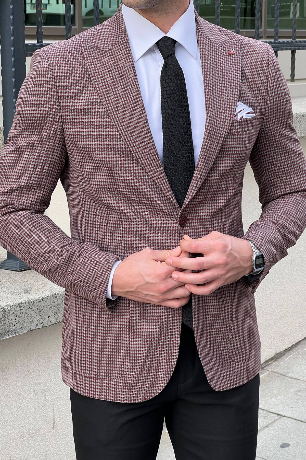 Man wearing a brown checkered blazer over a white shirt with a black tie.