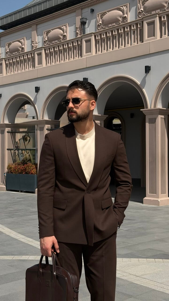 Man in a brown suit standing in an architectural setting