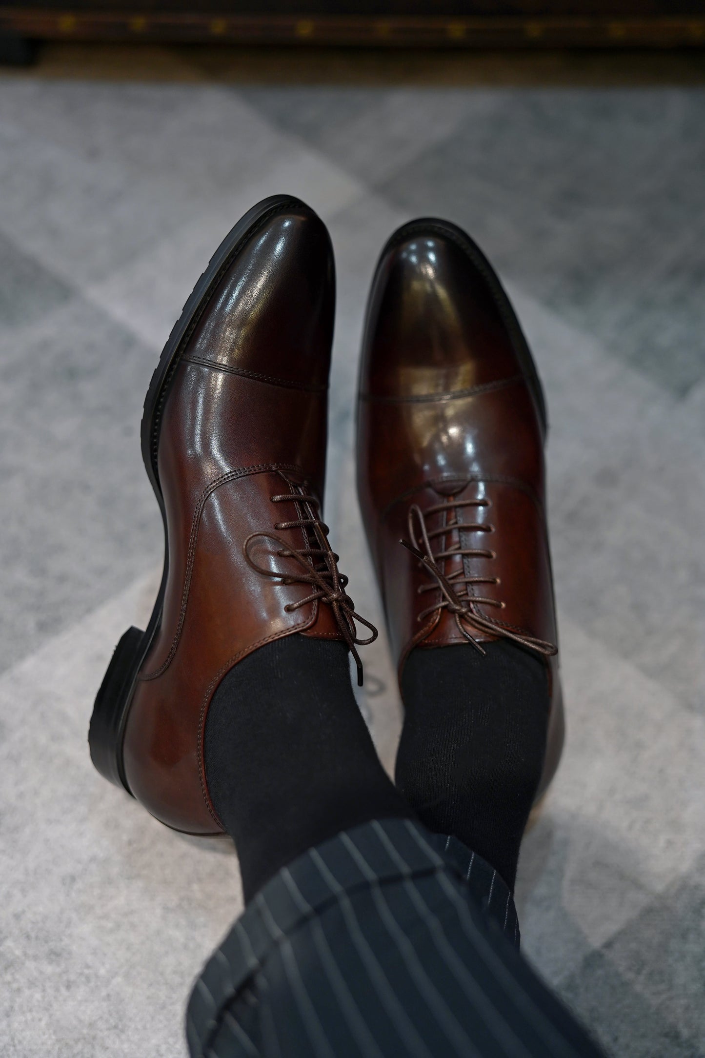 Close-up of men's espresso brown leather oxford shoes with a cap-toe design.