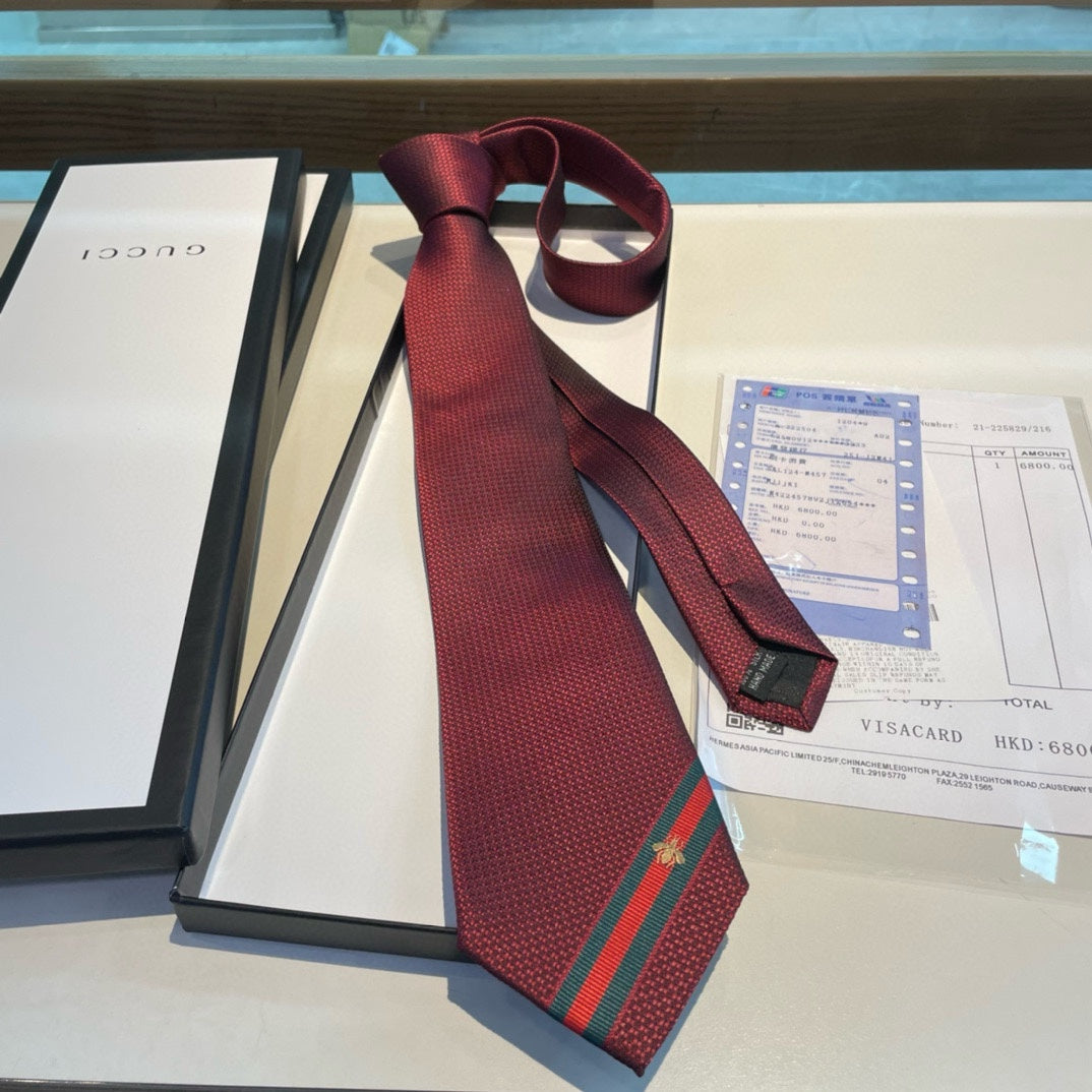 A burgundy silk tie with green and red stripes and a Gucci emblem, displayed on a table with a bill and a menu.