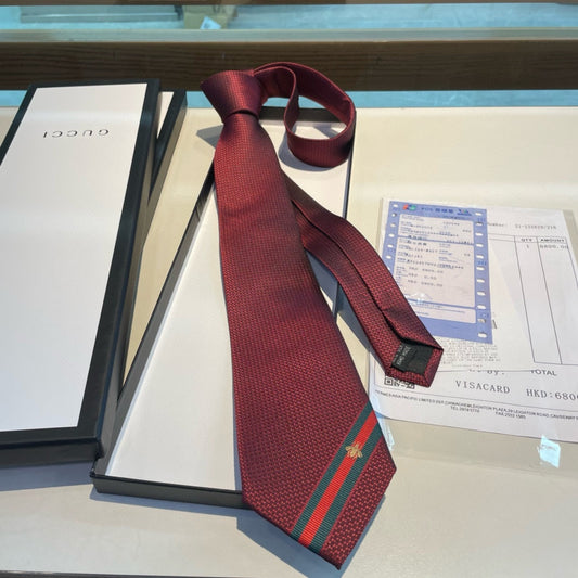A burgundy silk tie with green and red stripes and a Gucci emblem, displayed on a table with a bill and a menu.