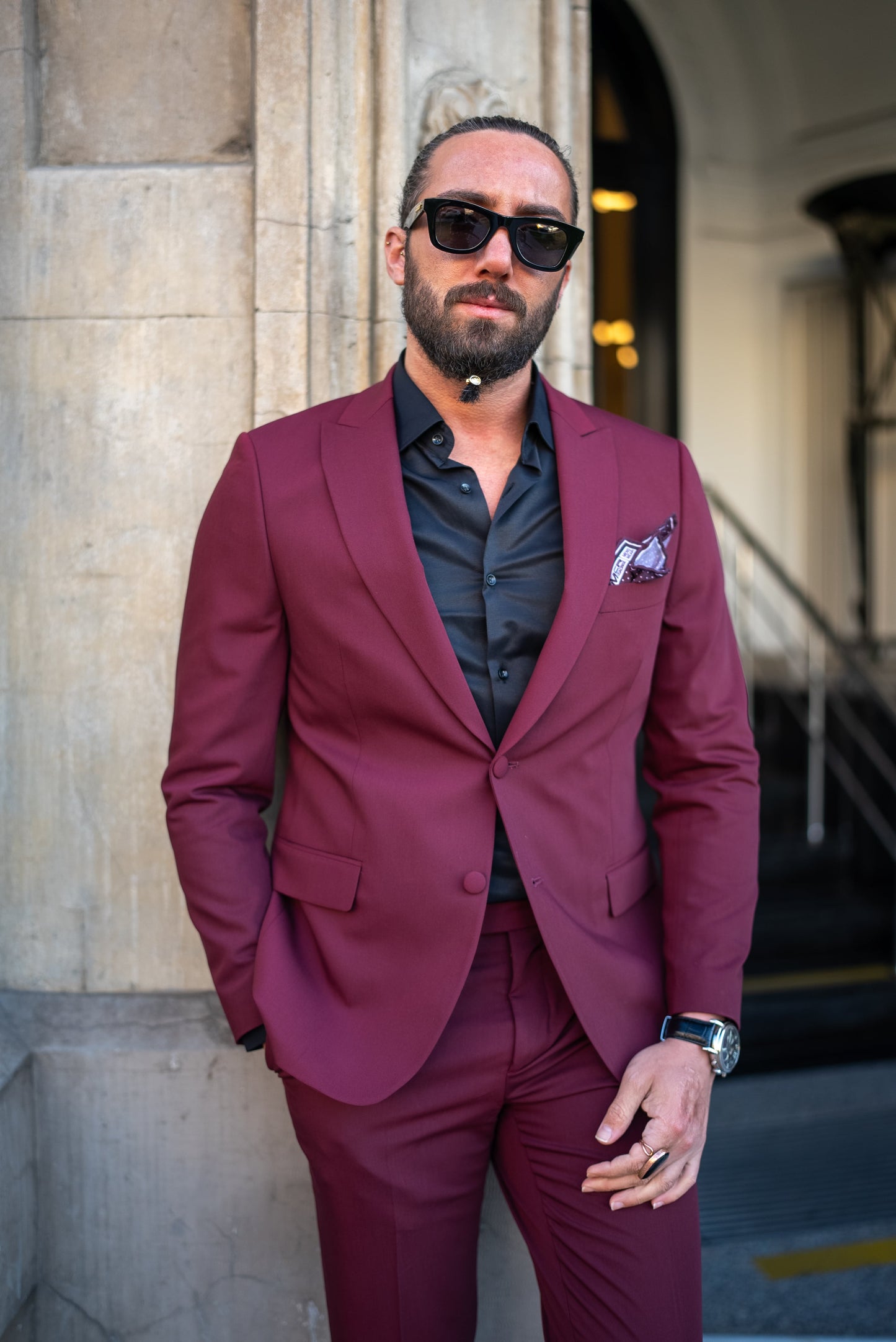 Man wearing a burgundy Italian cut tuxedo suit, paired with a black shirt, perfect for men's fall fashion and formal events.
