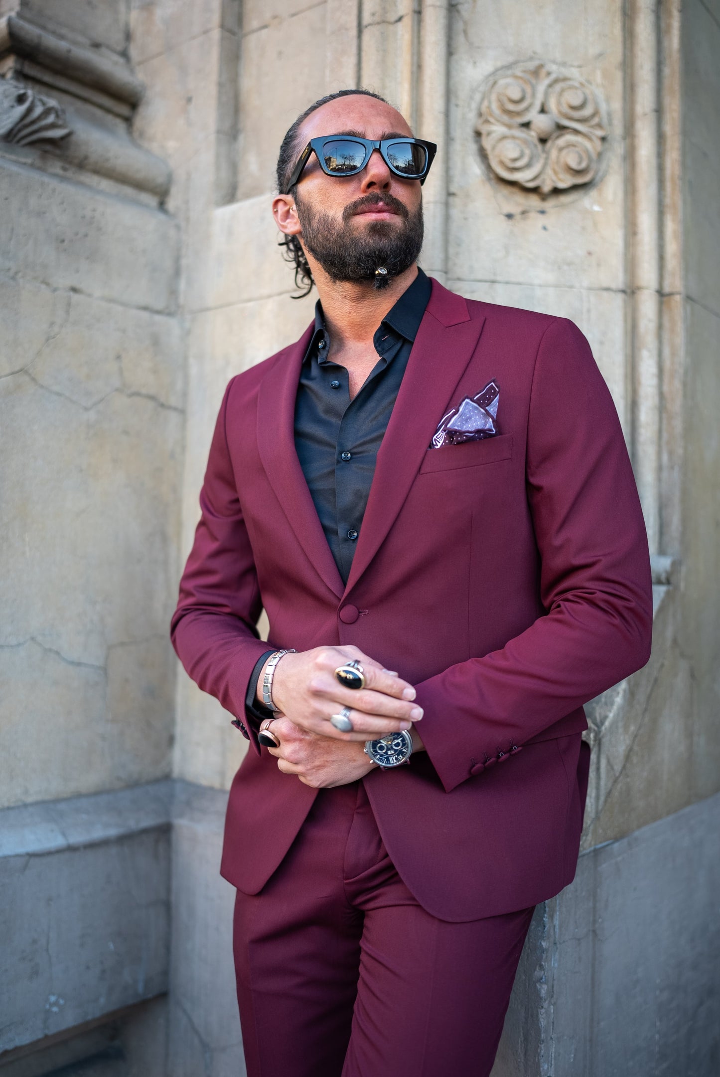 Man wearing a burgundy Italian cut tuxedo suit, paired with a black shirt, perfect for men's fall fashion and formal events.