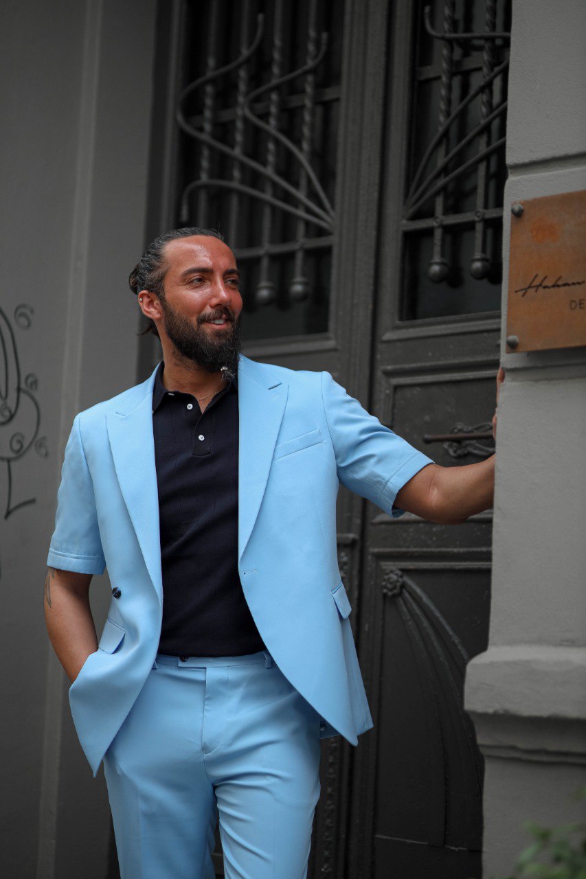 Man wearing light blue slim-fit summer suit smiling outdoors, breathable and elegant men’s attire
