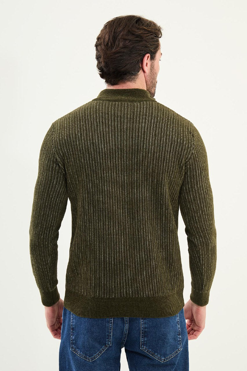 Man wearing a green ribbed sweater and blue jeans on a white background