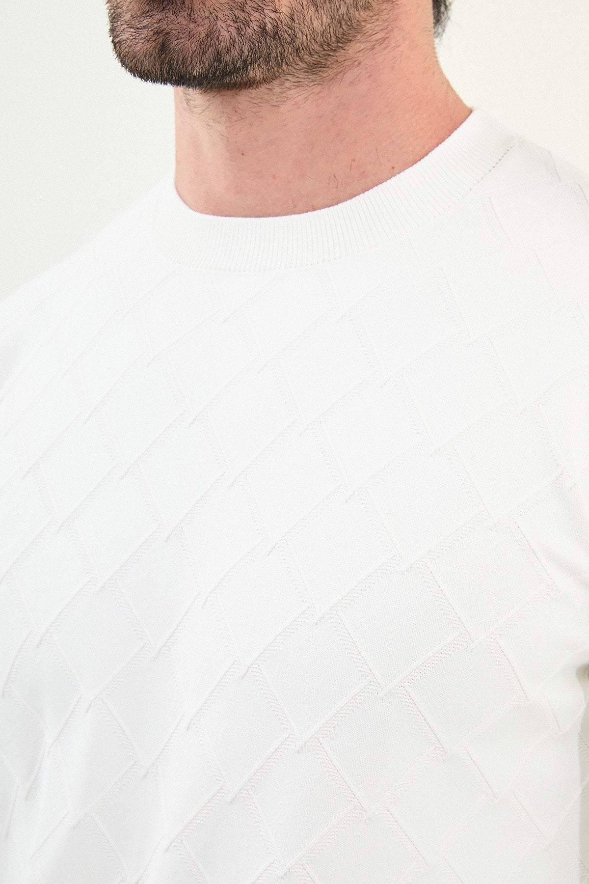 Close-up of a person wearing a white sweater with a textured pattern.