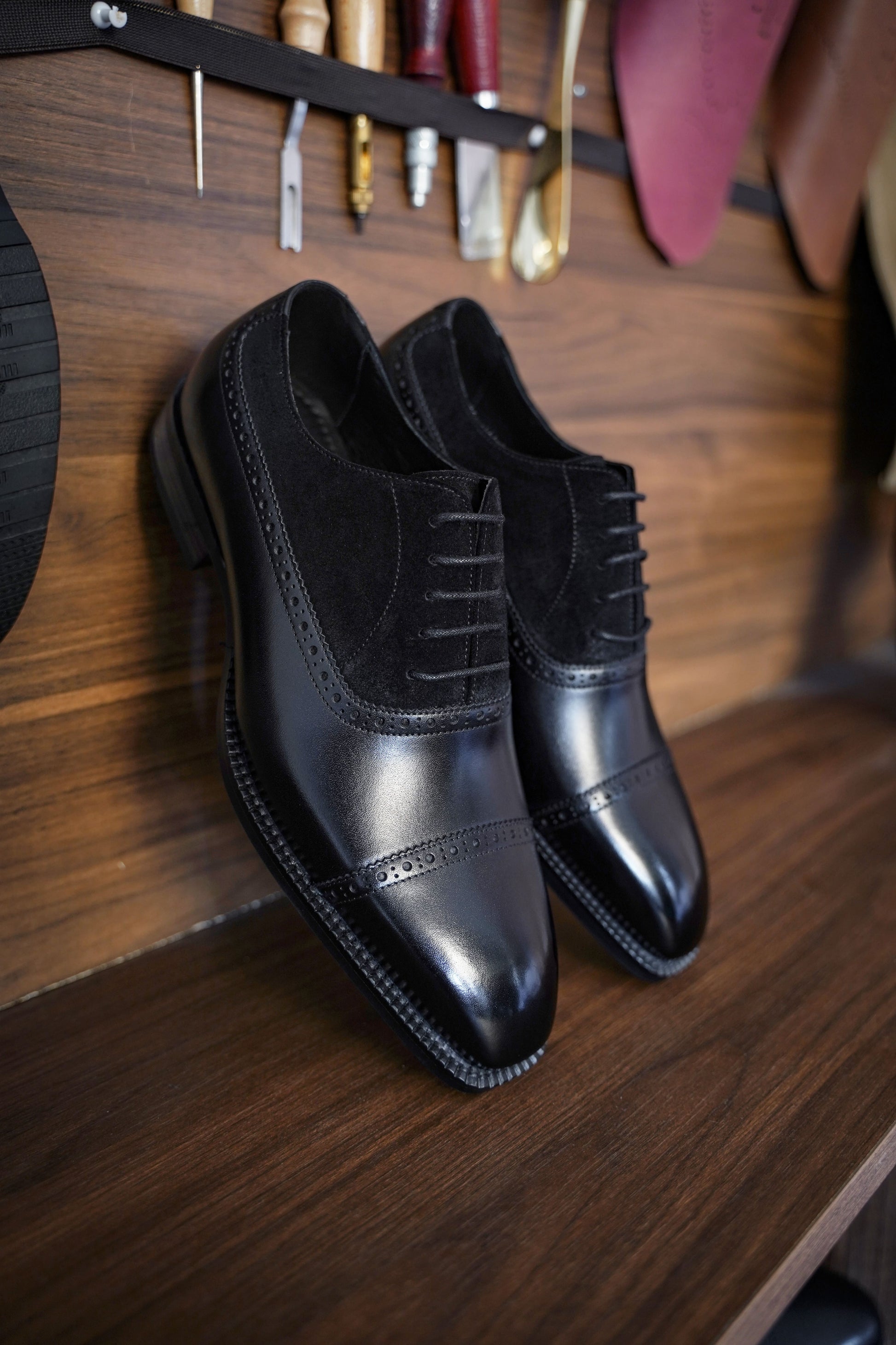 Close-up of men's black leather and suede oxfords with cap-toe detailing, showcasing a refined two-tone design perfect for formal attire.