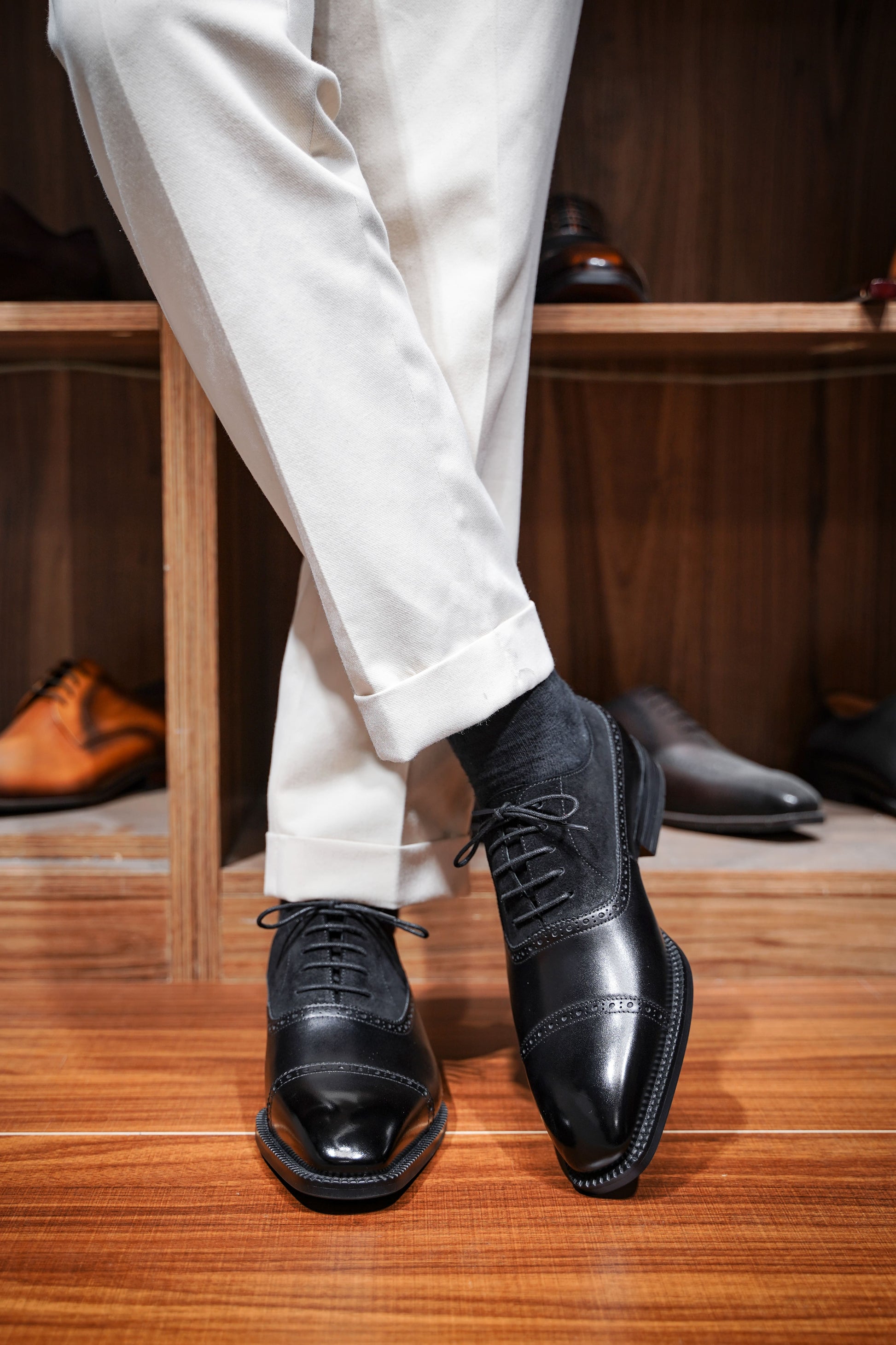Close-up of men's black leather and suede oxfords with cap-toe detailing, showcasing a refined two-tone design perfect for formal attire.