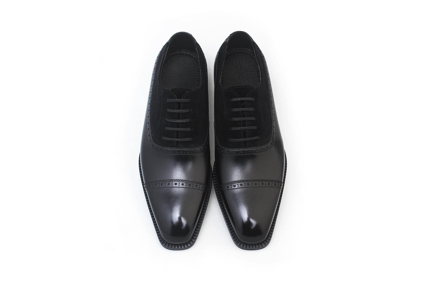 Close-up of men's black leather and suede oxfords with cap-toe detailing, showcasing a refined two-tone design perfect for formal attire.