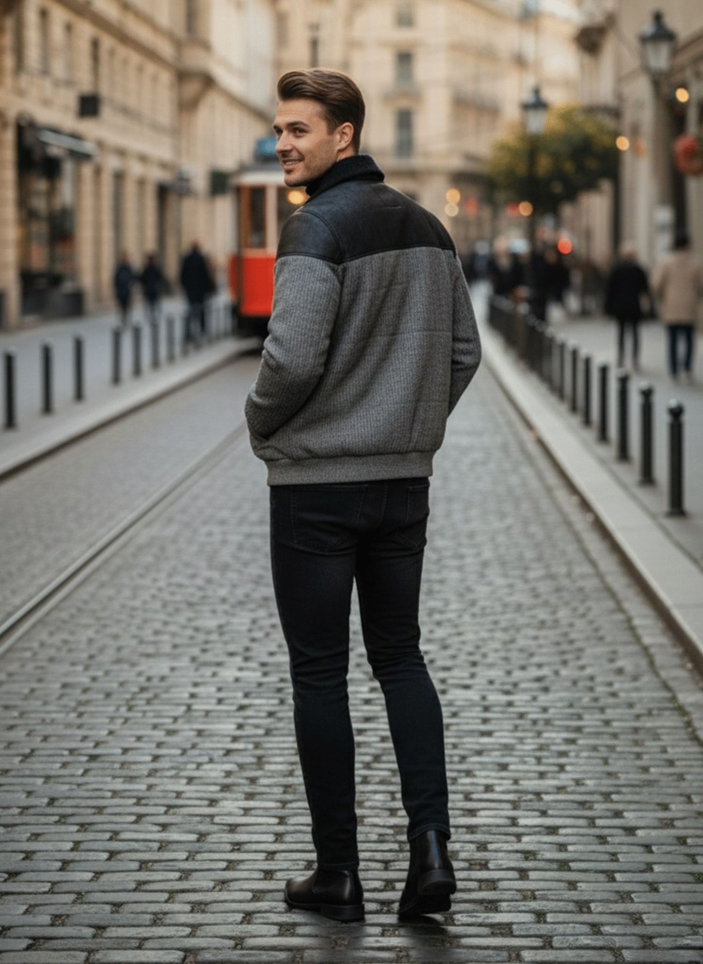Man walking down a city street wearing a gray sweater and black pants.