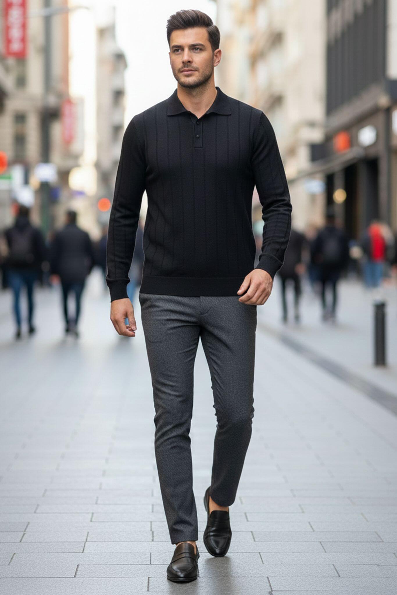 Man walking on a city street wearing a black sweater and gray pants.