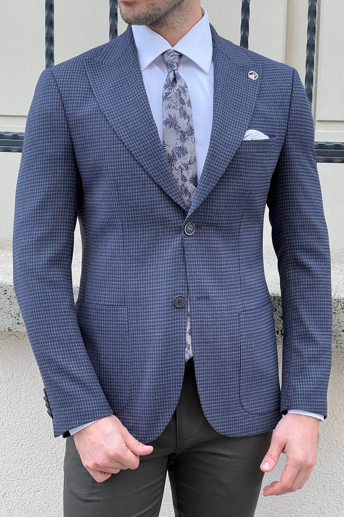 Man wearing a blue checkered suit with a patterned tie and pocket square.
