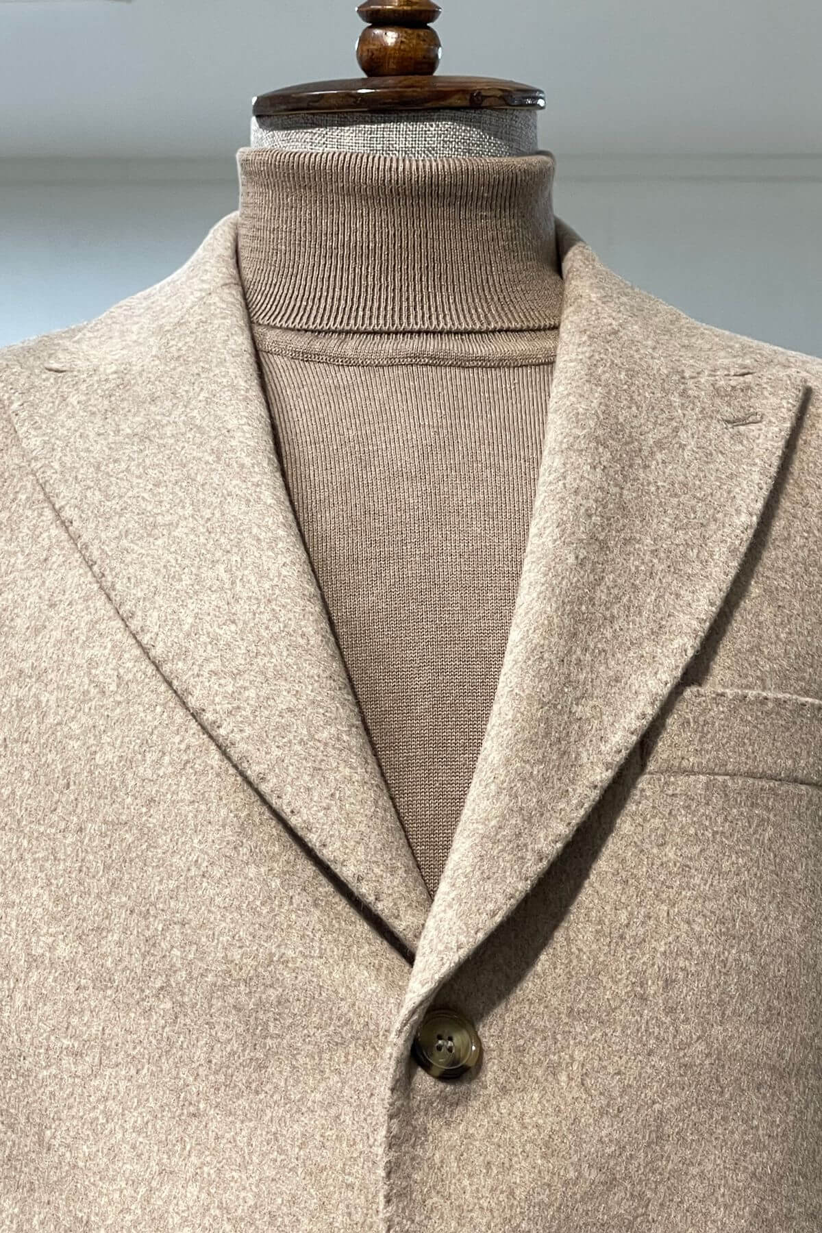 Beige blazer on a mannequin with a plain background