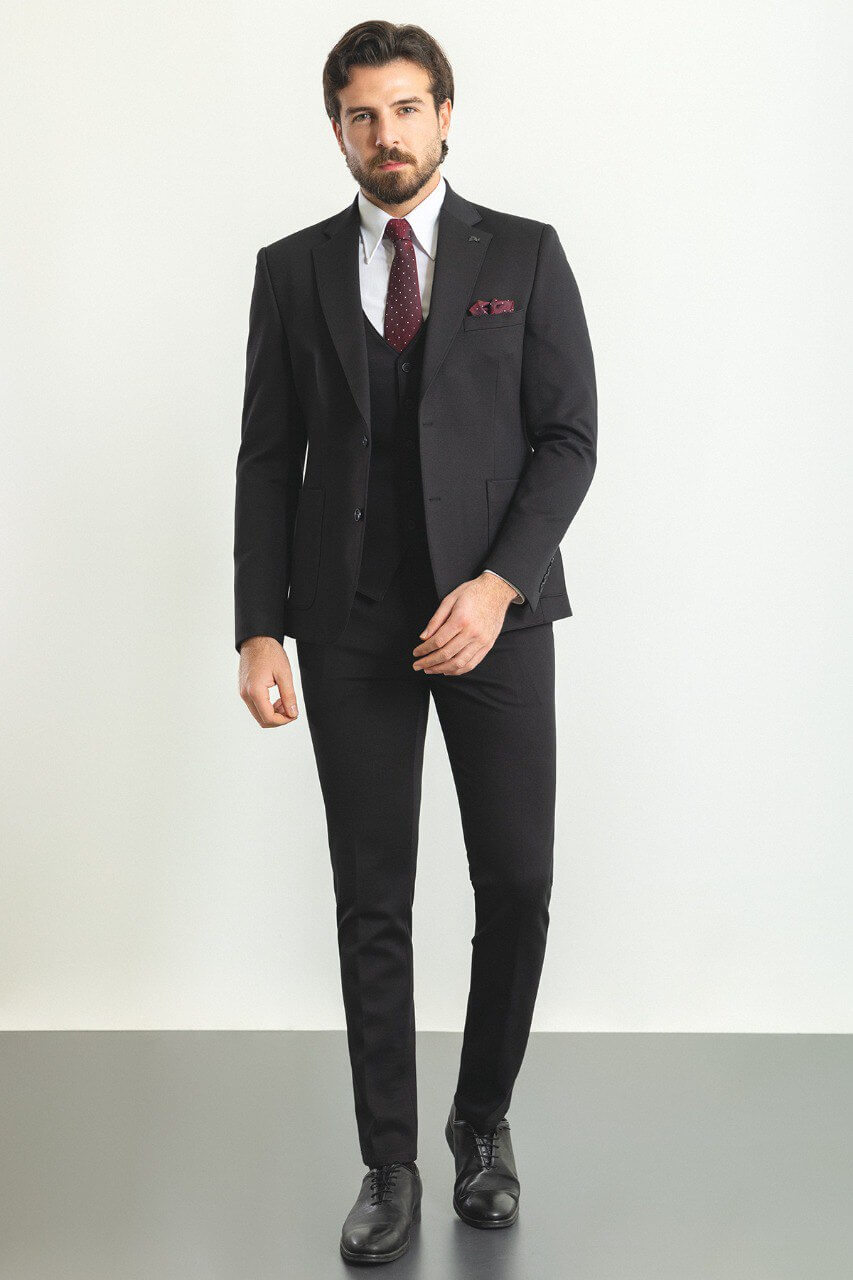 Man in a black 3-piece suit with a burgundy tie and pocket square.
