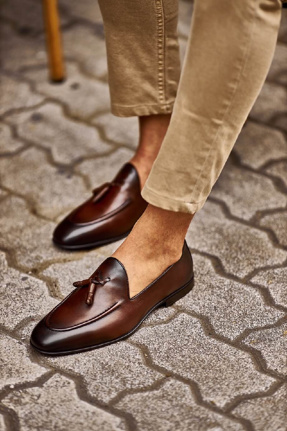 Close-up of stylish brown tassel loafers paired with beige pants, perfect for a casual yet refined look.