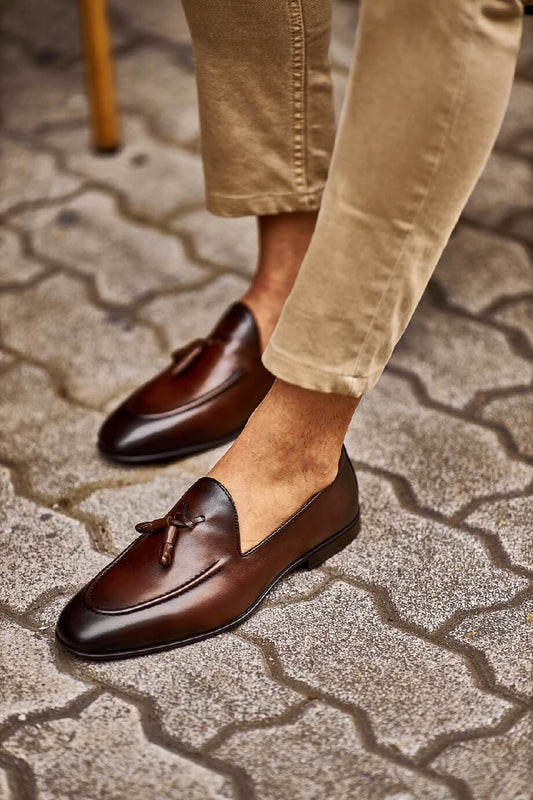 Close-up of stylish brown tassel loafers paired with beige pants, perfect for a casual yet refined look.