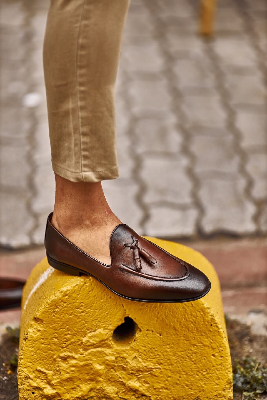 Close-up of stylish brown tassel loafers paired with beige pants, perfect for a casual yet refined look.