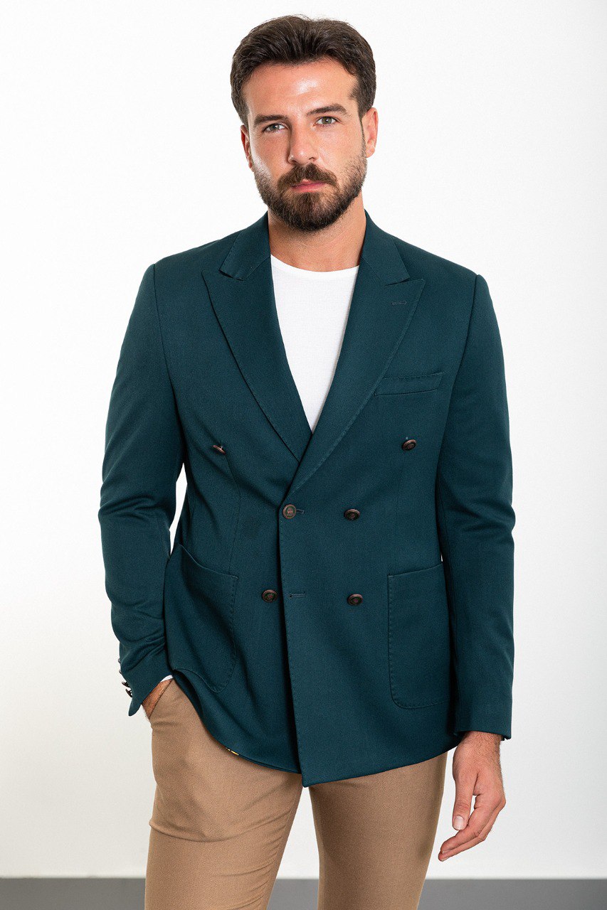 Man wearing a teal double-breasted blazer paired with beige trousers,.
