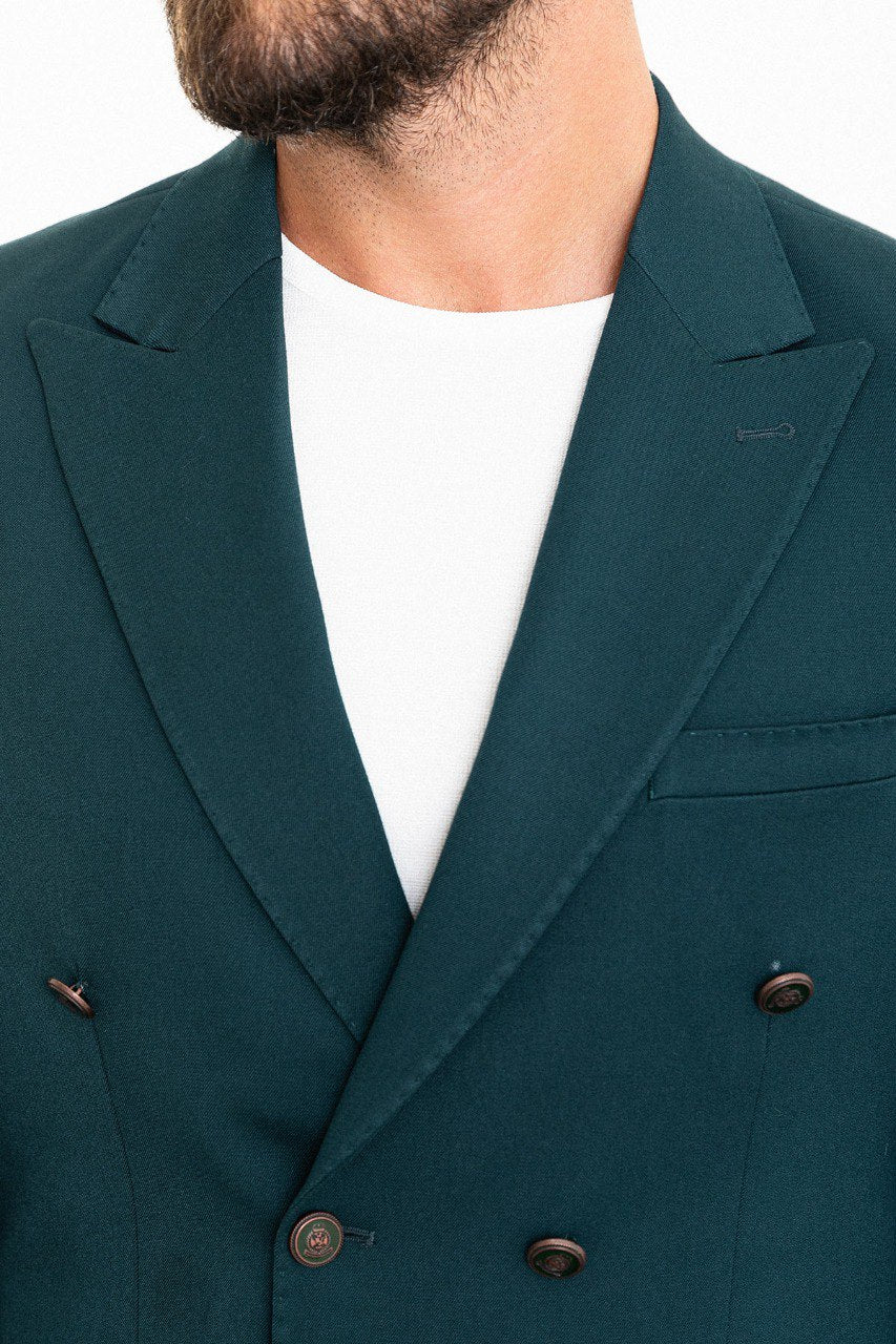 Man wearing a teal double-breasted blazer paired with beige trousers.