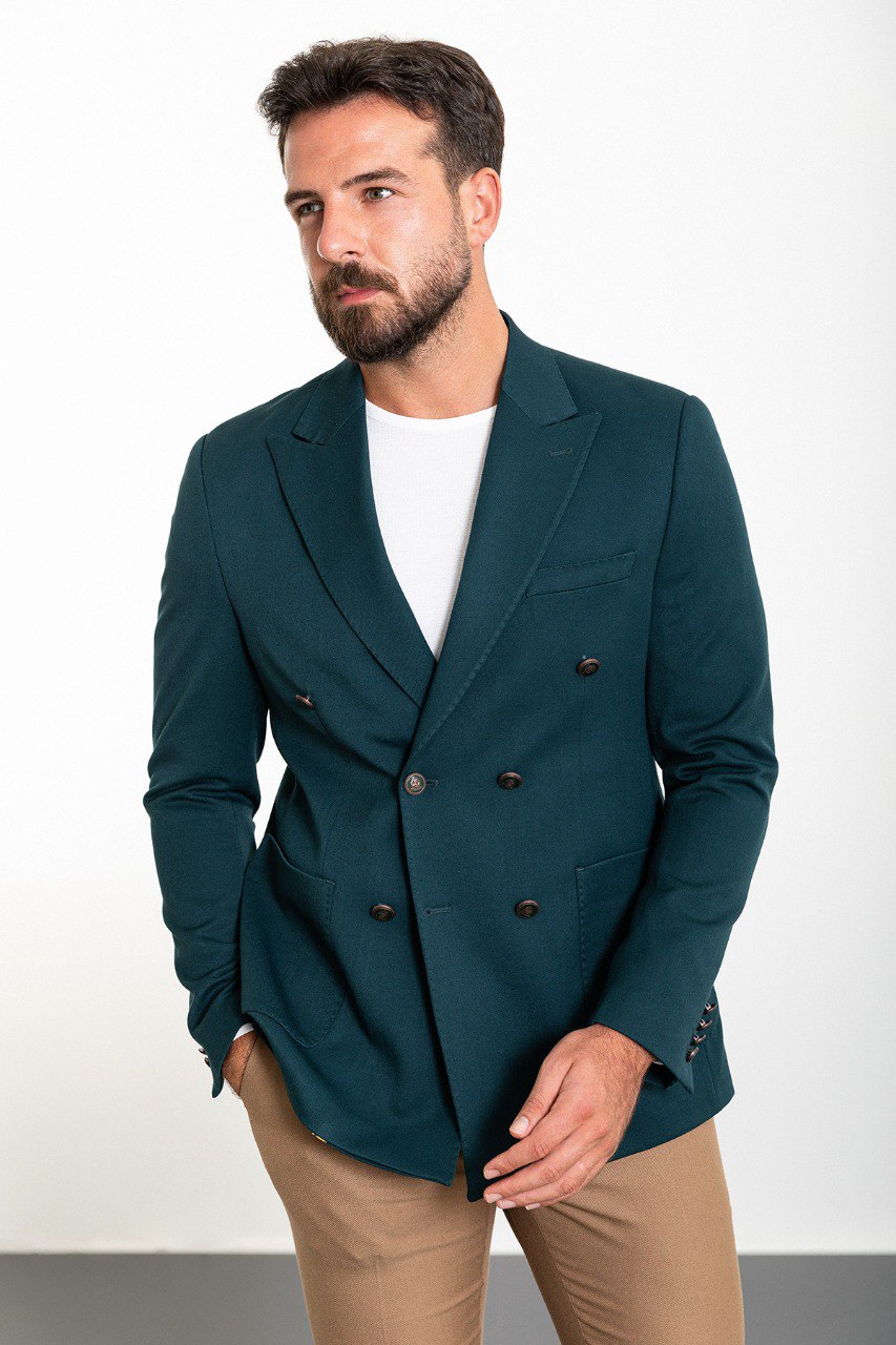 Man wearing a teal double-breasted blazer paired with beige trousers.