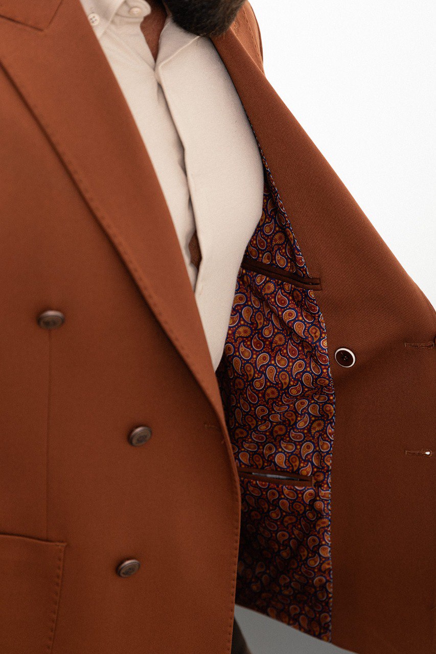 Man in a stylish brown double-breasted blazer paired with a beige shirt.