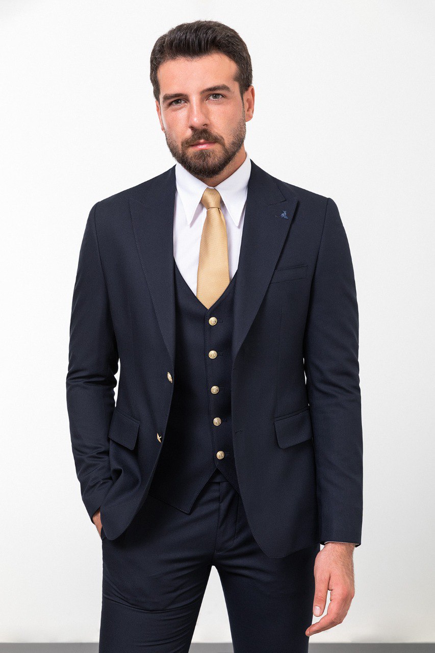 Man wearing a navy blue 3-piece suit with a gold tie.