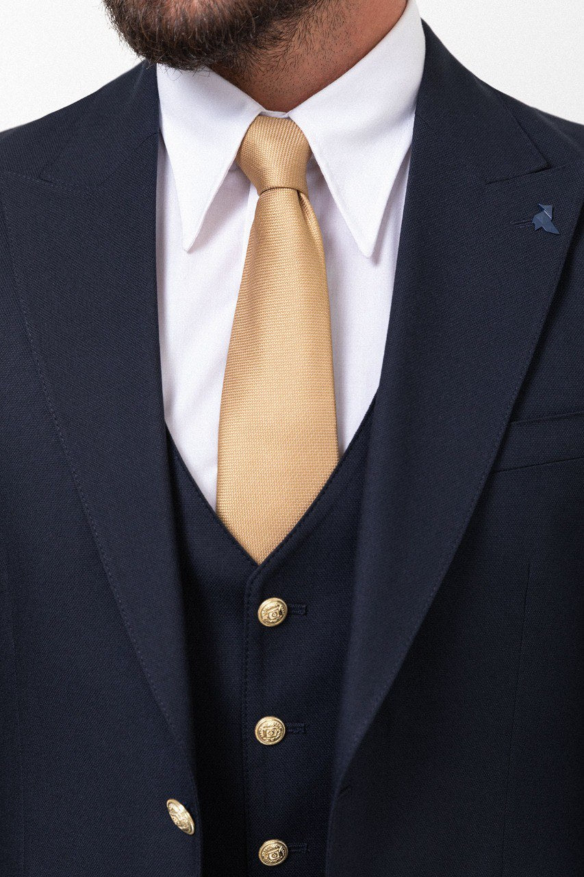 Man wearing a navy blue 3-piece suit with a gold tie.