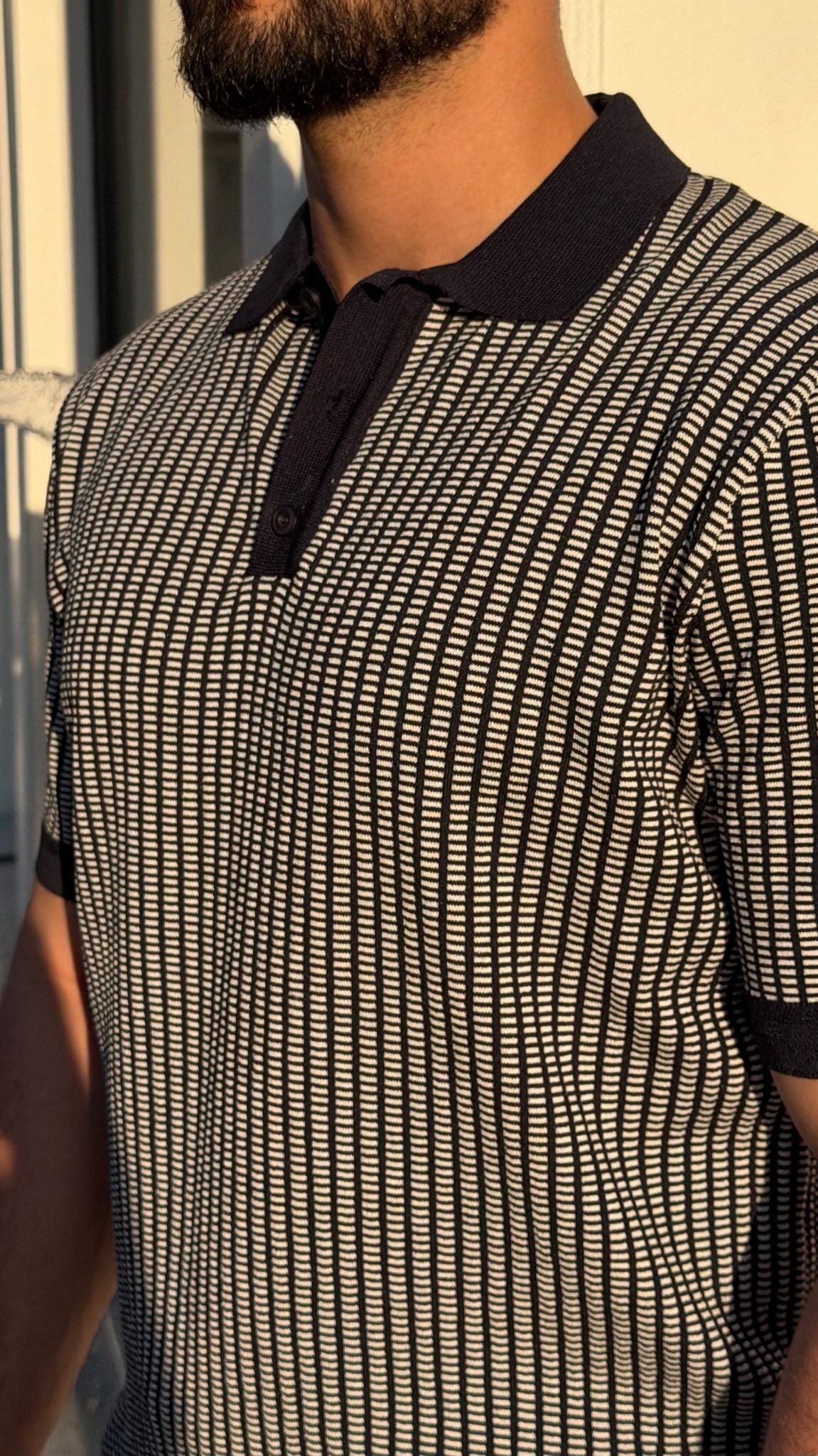 Close-up of men's navy blue textured knit polo shirt collar and button placket