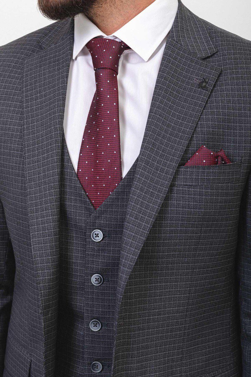 Man wearing a dark gray checkered suit with a burgundy tie and pocket square.