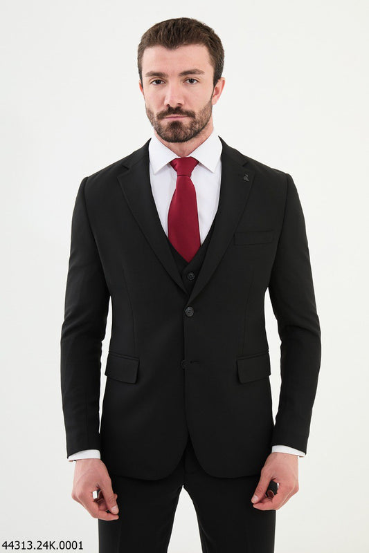 A man wearing a black slim fit three-piece business suit with a white shirt and a red tie.