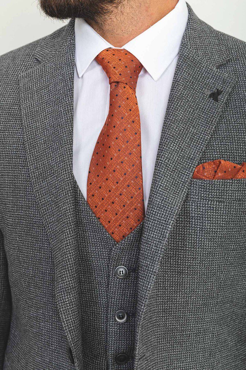 Man wearing a plaid dark gray 3-piece suit with an orange tie and pocket square.