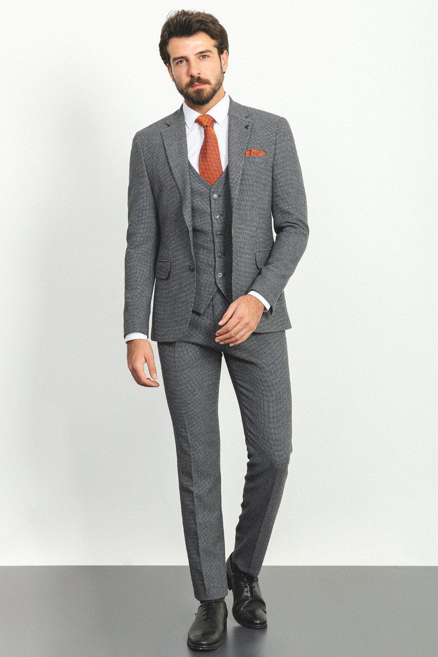 Man wearing a plaid dark gray 3-piece suit with an orange tie and pocket square.