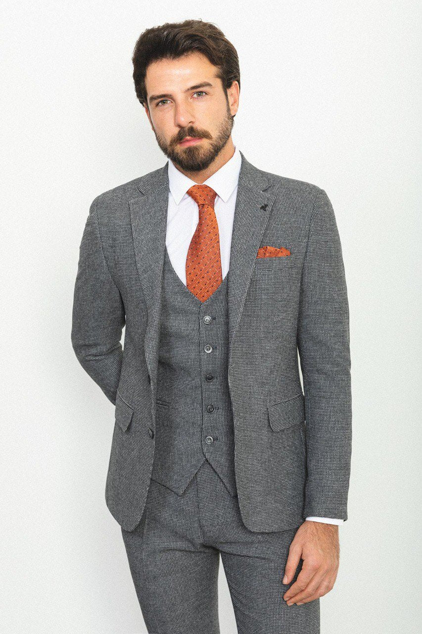 Man wearing a plaid dark gray 3-piece suit with an orange tie and pocket square.