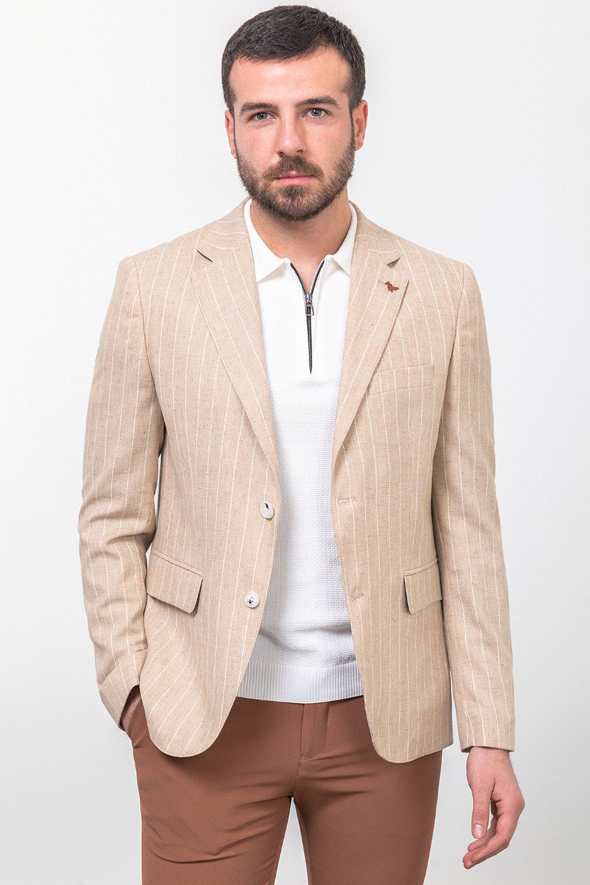 Man wearing a beige pinstripe blazer paired with brown trousers.